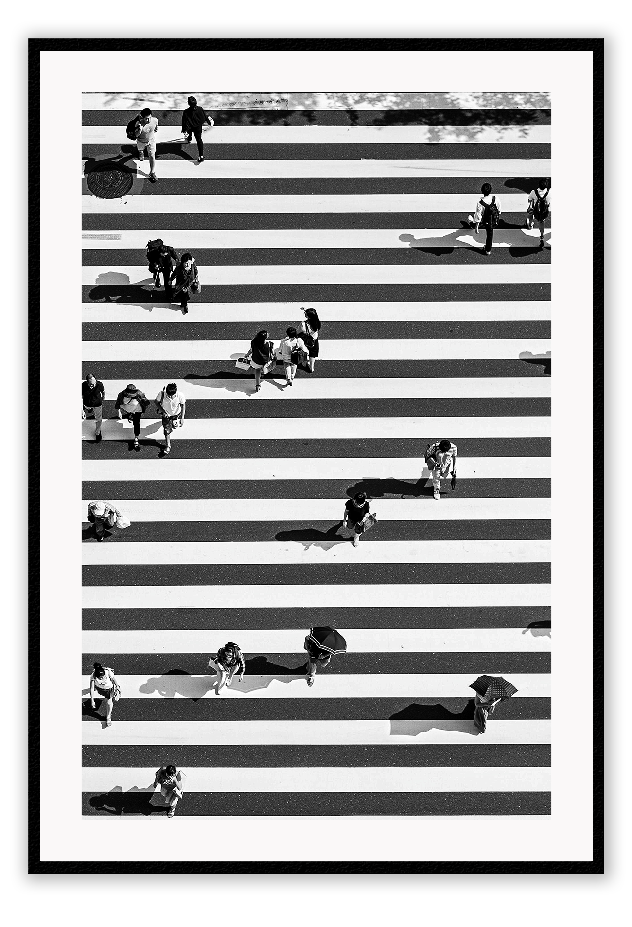 A black and white urban wall art with an aerial view of a busy city street crossing with zebra stripes.