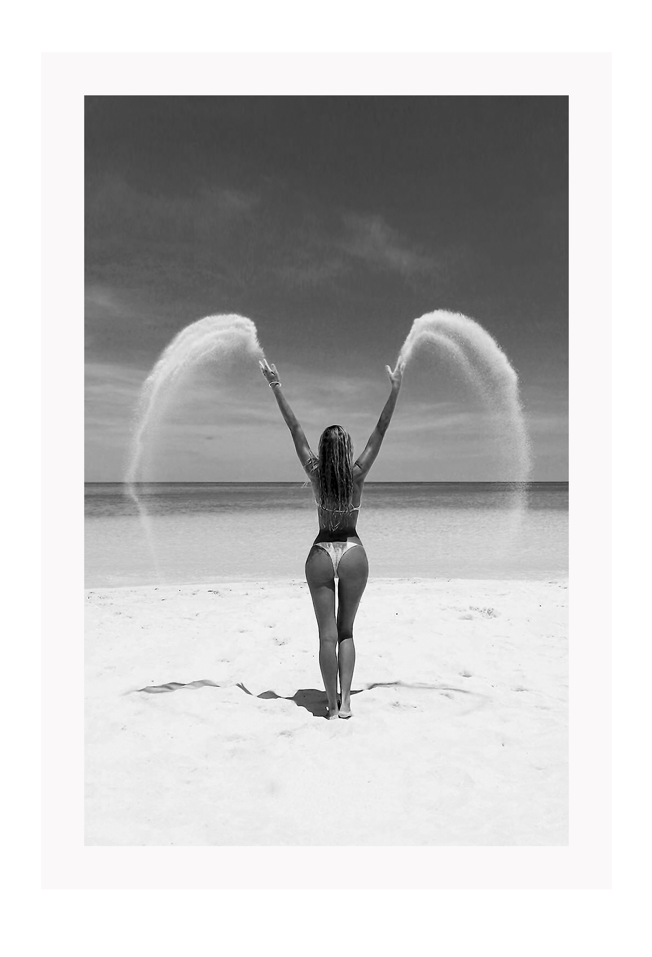 Sexy lady woman throwing sand on a beach in black and white, coastal ocean. 