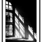 A black and white wall art with sunlight penetrating through big windows casting window shadows and creating high contrast.  