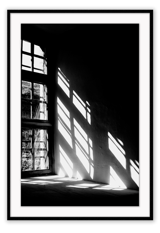 A black and white wall art with sunlight penetrating through big windows casting window shadows and creating high contrast.  