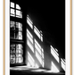 A black and white wall art with sunlight penetrating through big windows casting window shadows and creating high contrast.  