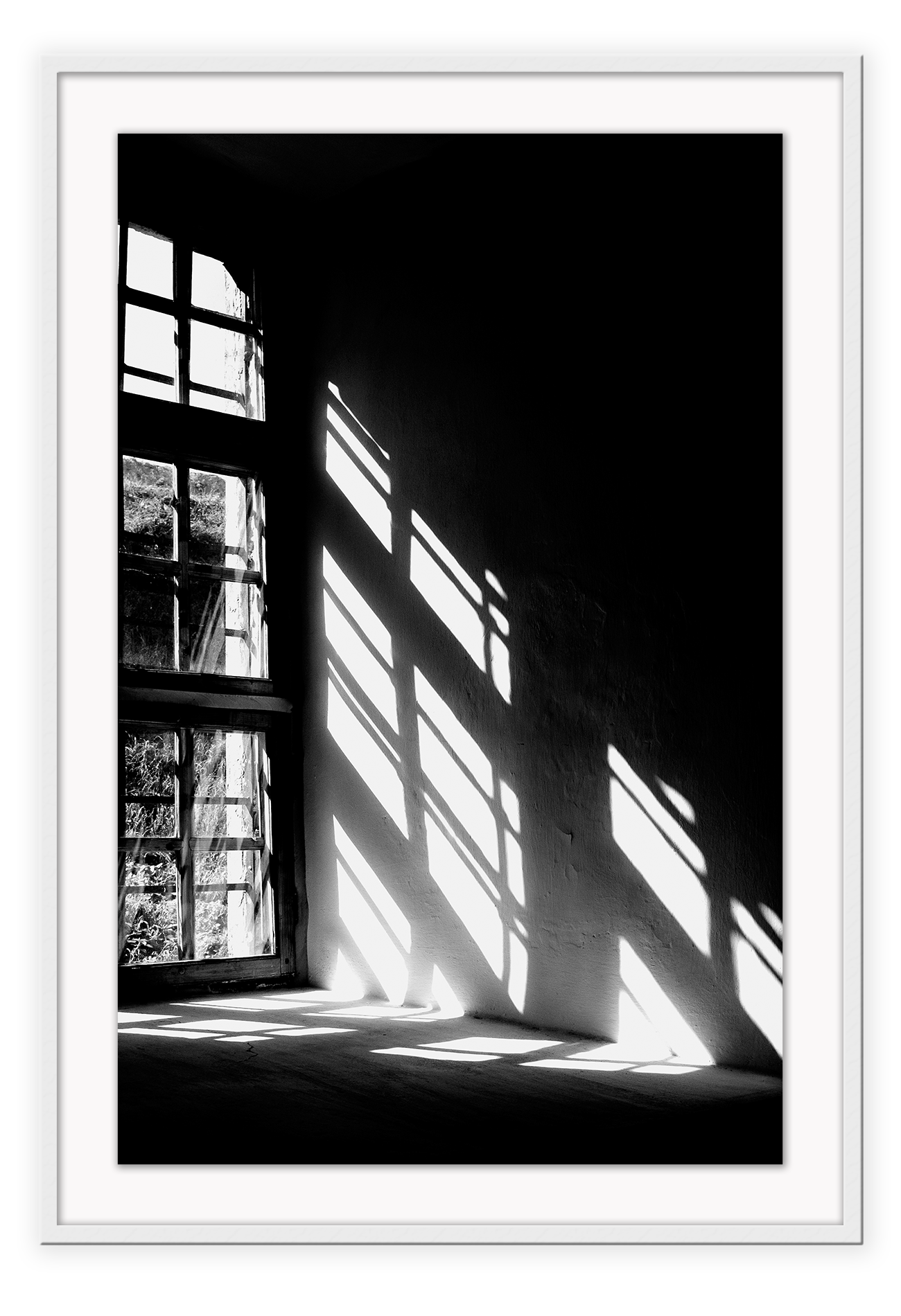 A black and white wall art with sunlight penetrating through big windows casting window shadows and creating high contrast.  