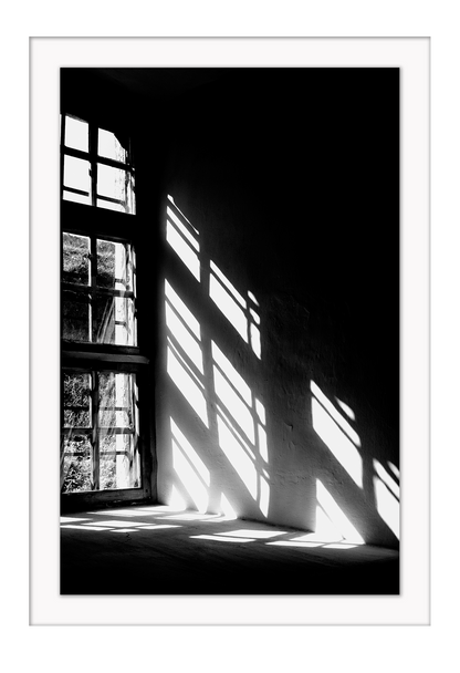 A black and white wall art with sunlight penetrating through big windows casting window shadows and creating high contrast.  